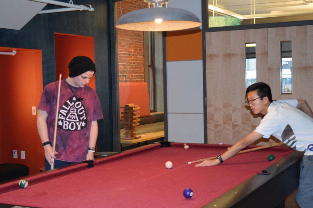 two international students play pool in the lobby of the student-hotel that they are staying at for thanksgiving break