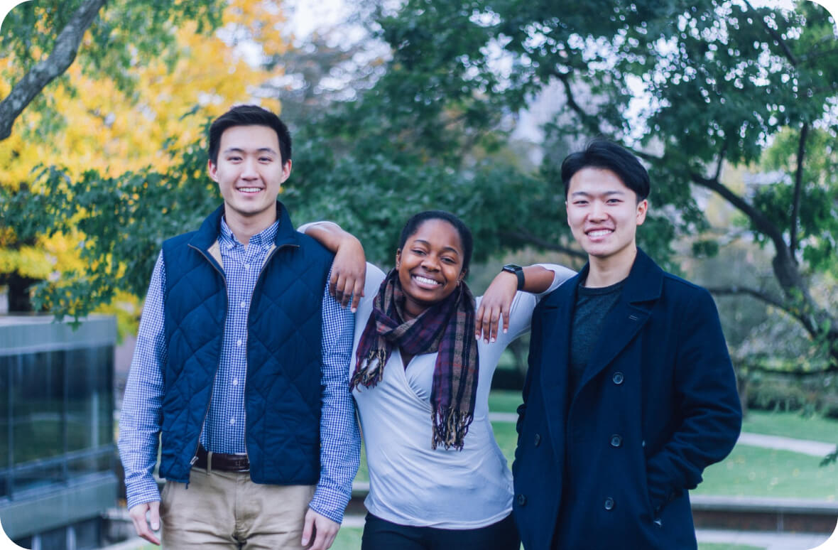 three international students pose for a group picture, smiling and enjoying the season of autumn in the USA